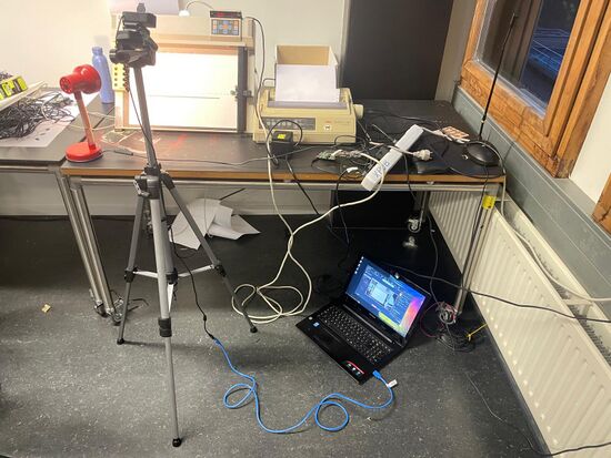 A webcam pointed to an XY-plotter connected to a livestreaming laptop